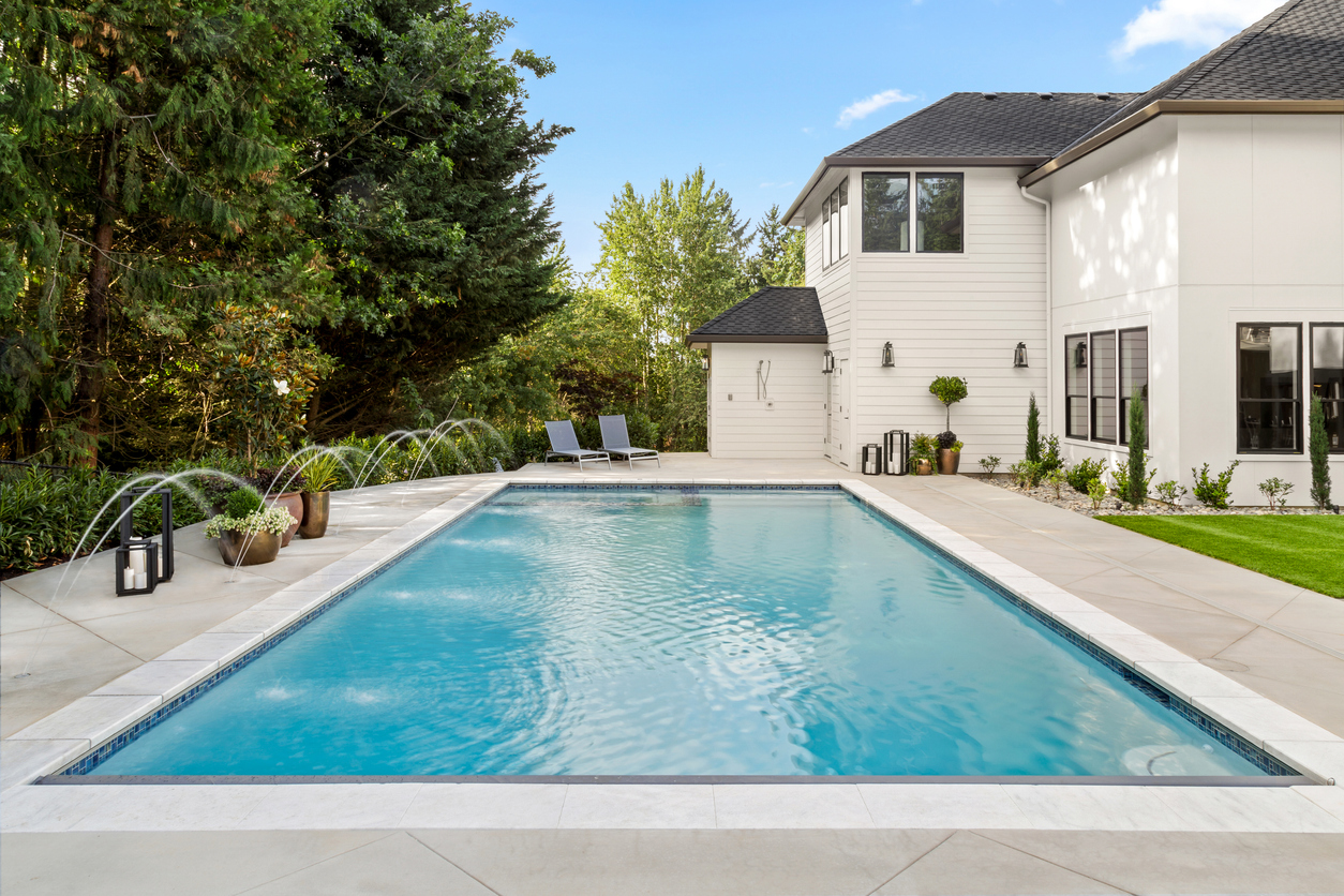 Rectangular pool with deck jets in front of a white modern home