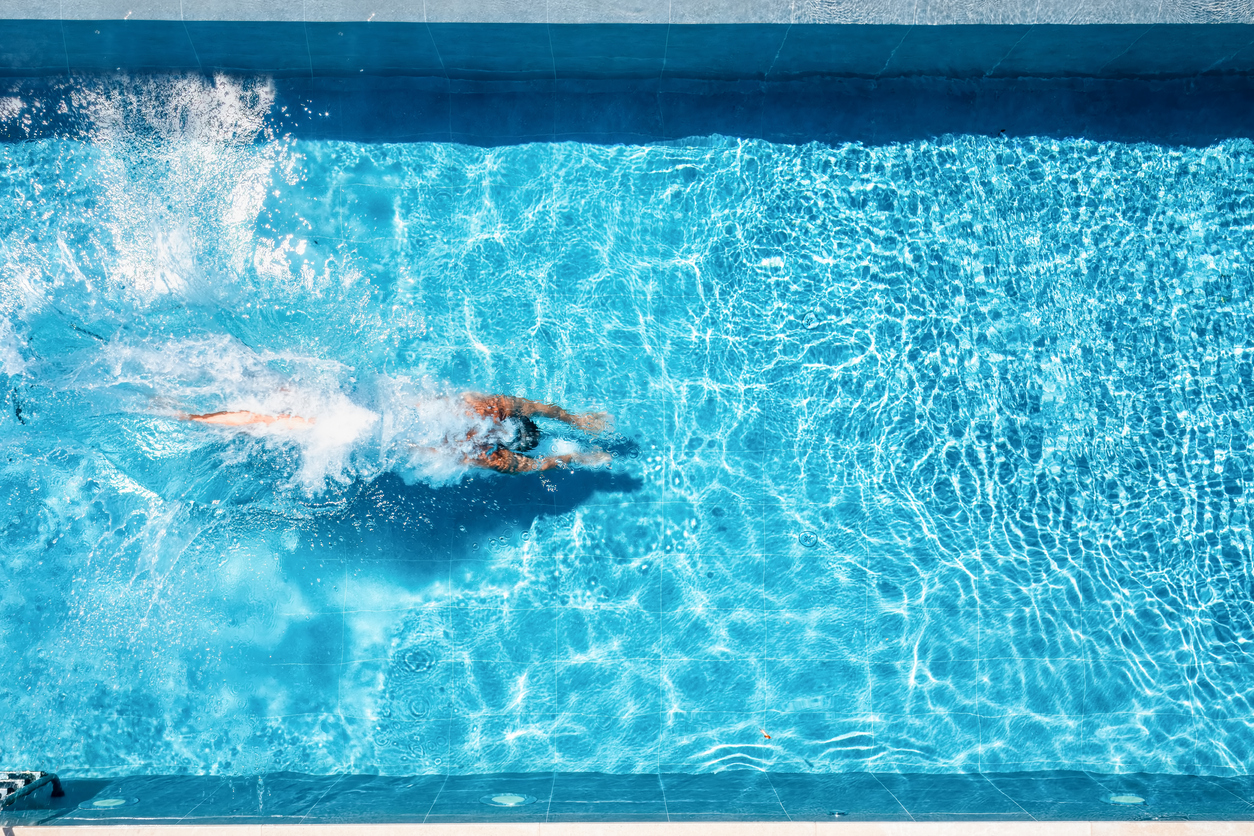 Aerial view of a swimmer diving into a sparkling blue pool